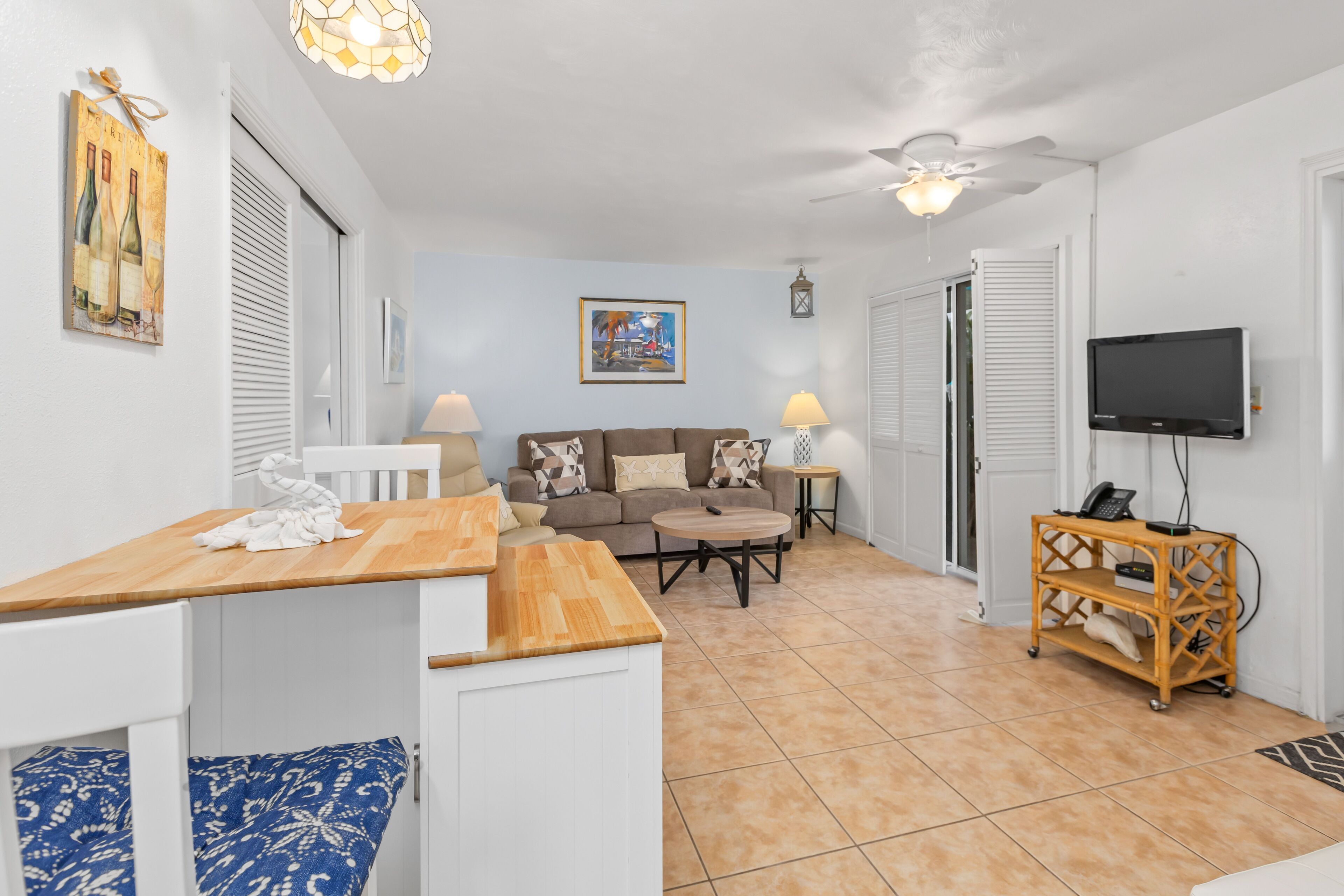 A compact living space with a kitchenette, a sofa, a TV, and a ceiling fan.