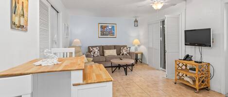 A compact living space with a kitchenette, a sofa, a TV, and a ceiling fan.