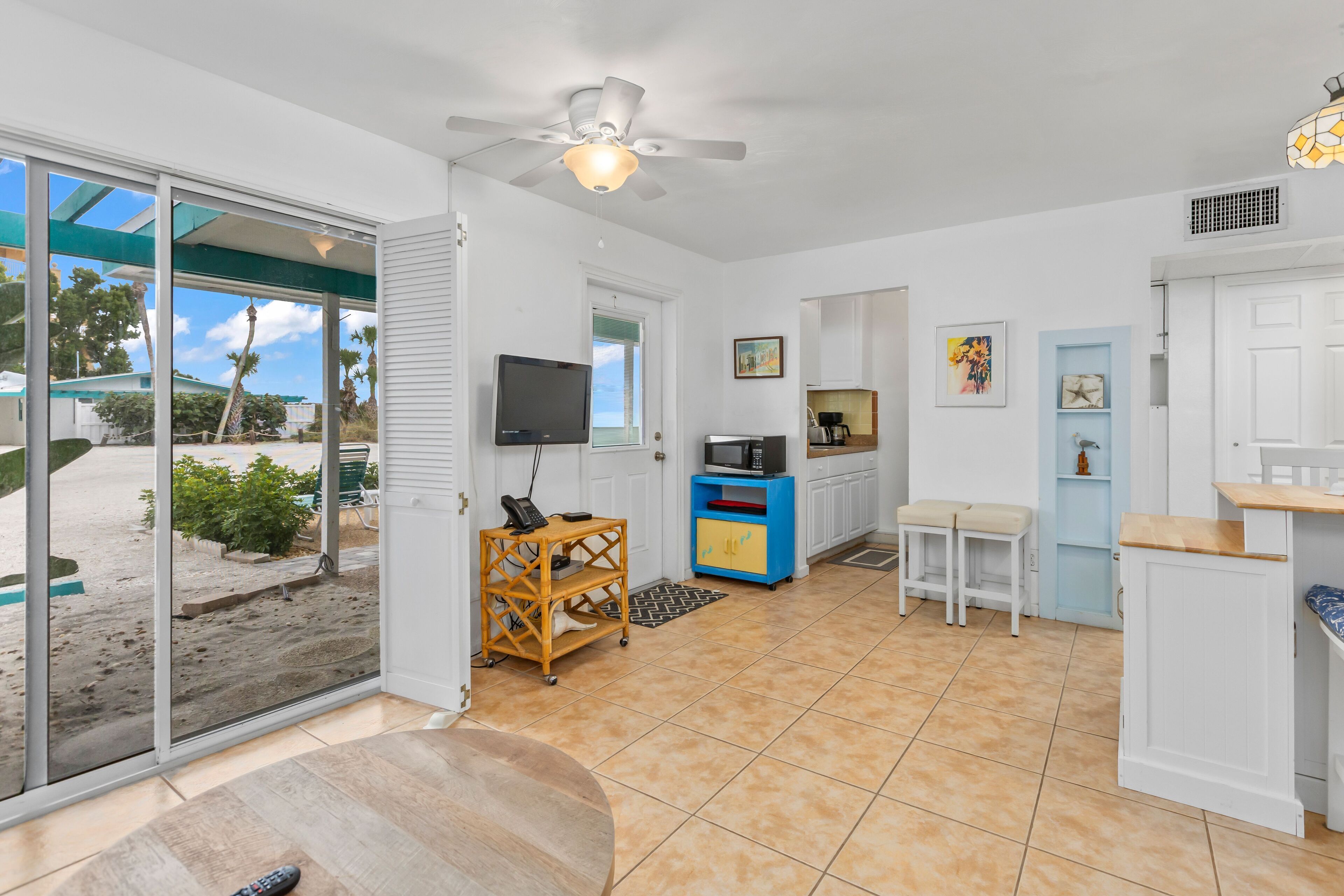 A spacious kitchen with a sliding glass door leading to a balcony, a ceiling fan, and a small dining area.