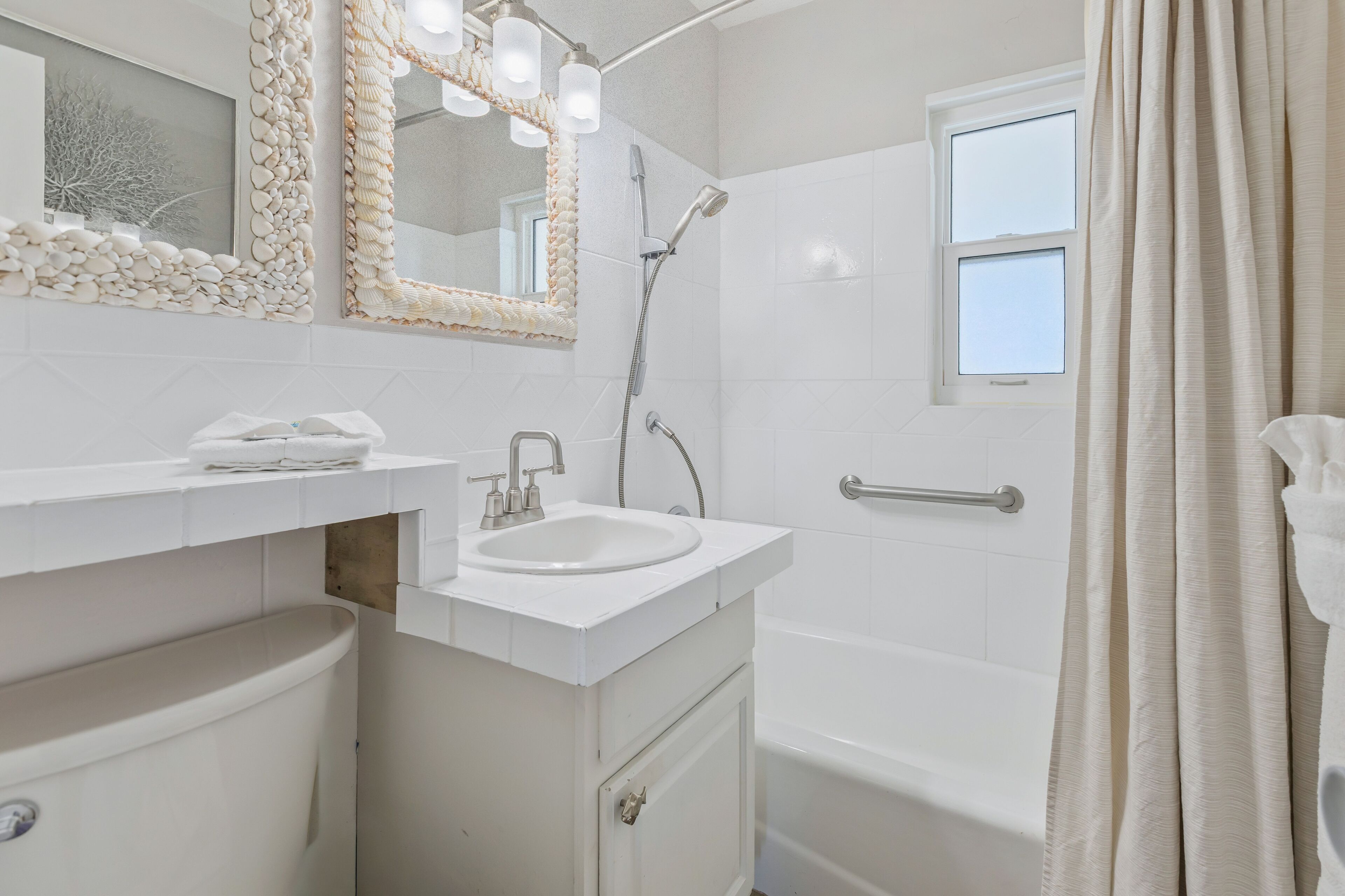 Une salle de bain avec un lavabo blanc, un miroir et une douche.