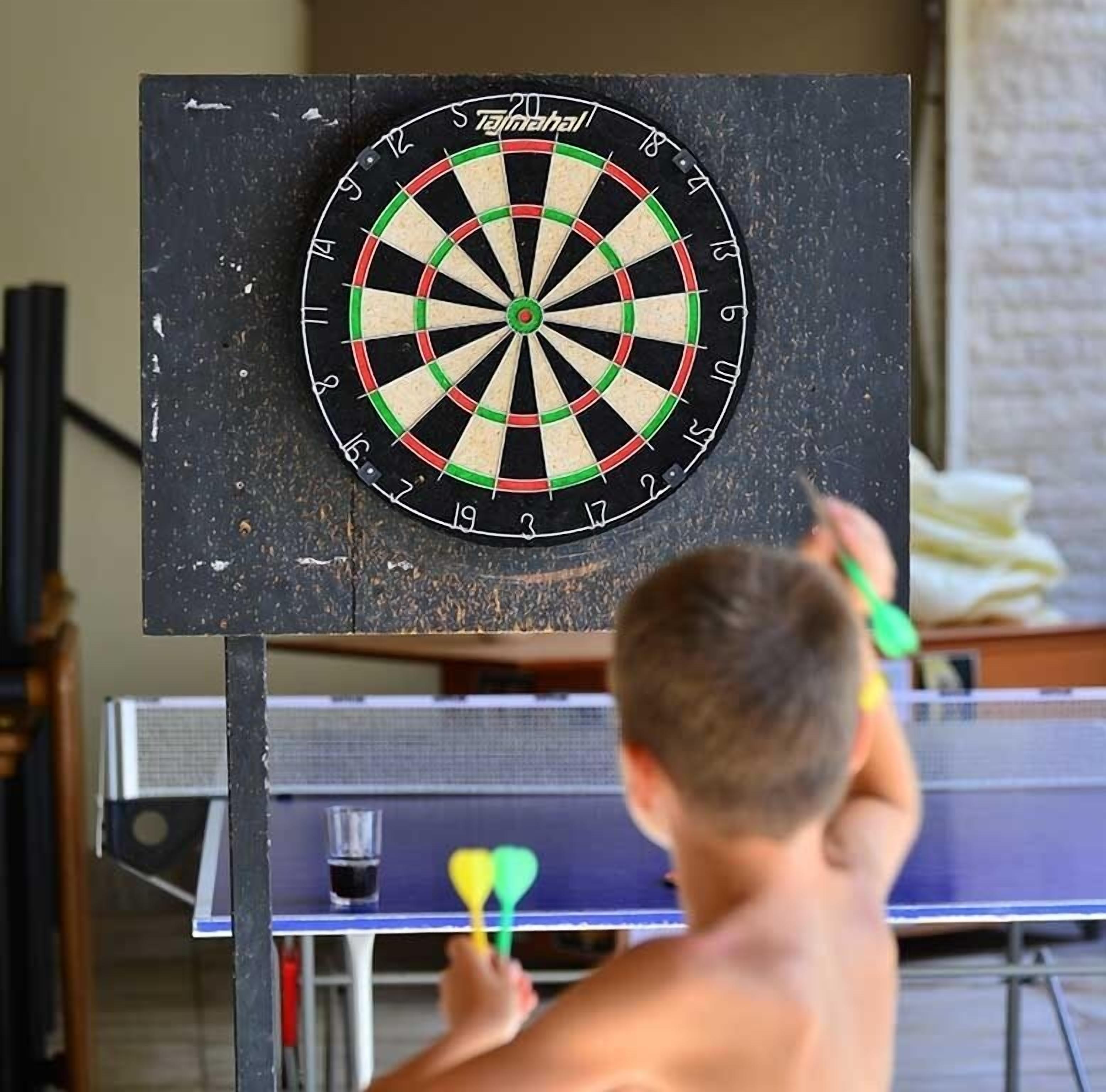 A dartboard mounted on a wall with a dartboard in front of a ping pong table.