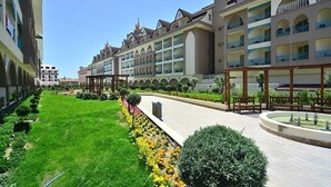 Un patio de hotel con un sendero central, rodeado de abundante vegetación y una fuente decorativa.
