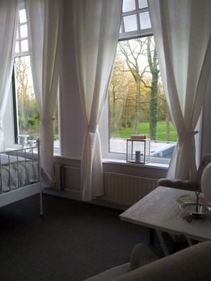 A room with a bed, a table, and a window with curtains. - Bed & Breakfast Rijsterbosch (Rijs)