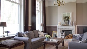 A living room with a fireplace, a sofa, a coffee table, and a window with curtains. - Bed & Breakfast Rijsterbosch (Rijs)