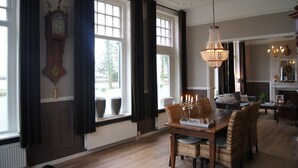 A dining area with a wooden table, wicker chairs, and a chandelier. - Bed & Breakfast Rijsterbosch (Rijs)