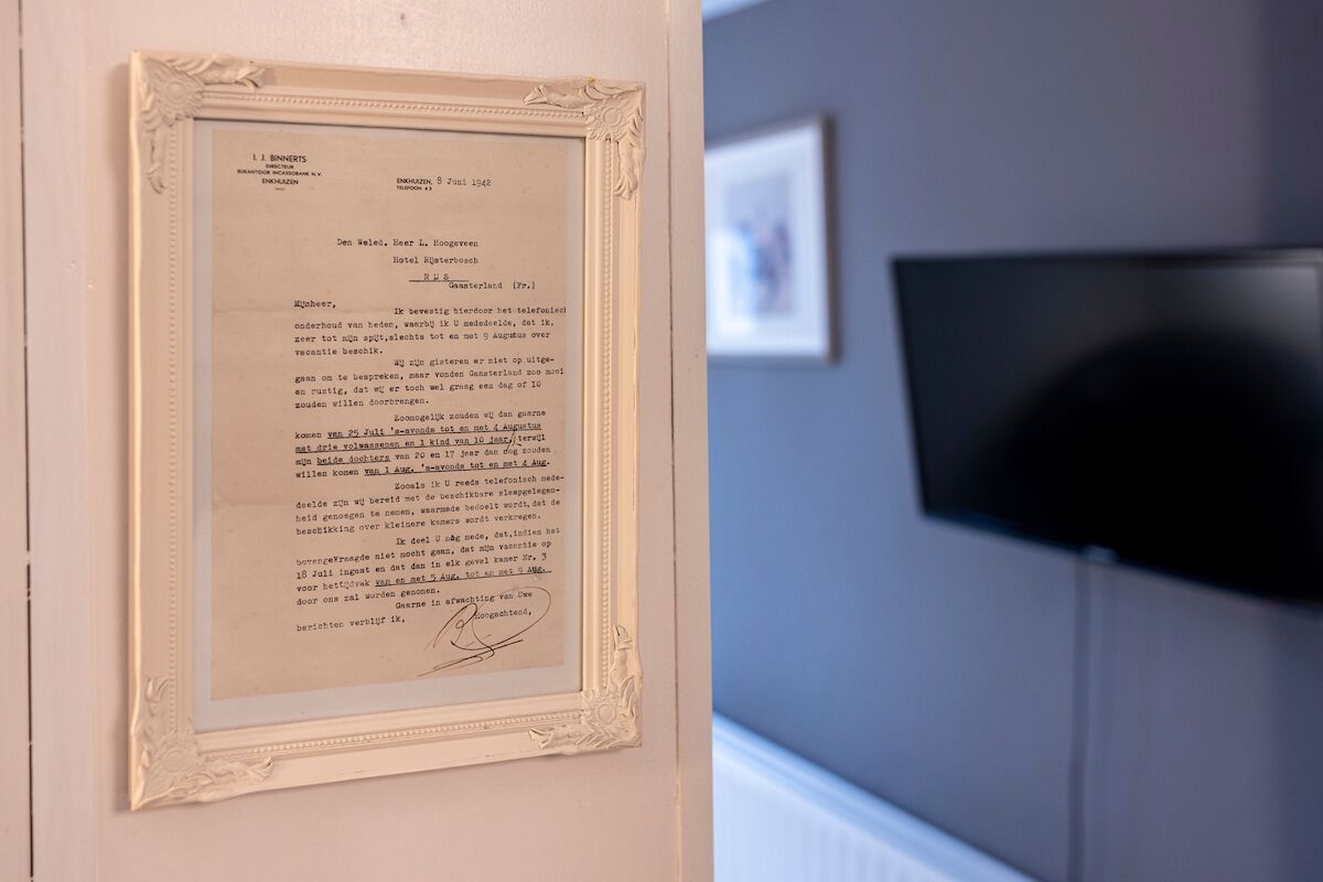 Una carta en un marco colgada en la pared, con una pantalla de televisión al fondo.