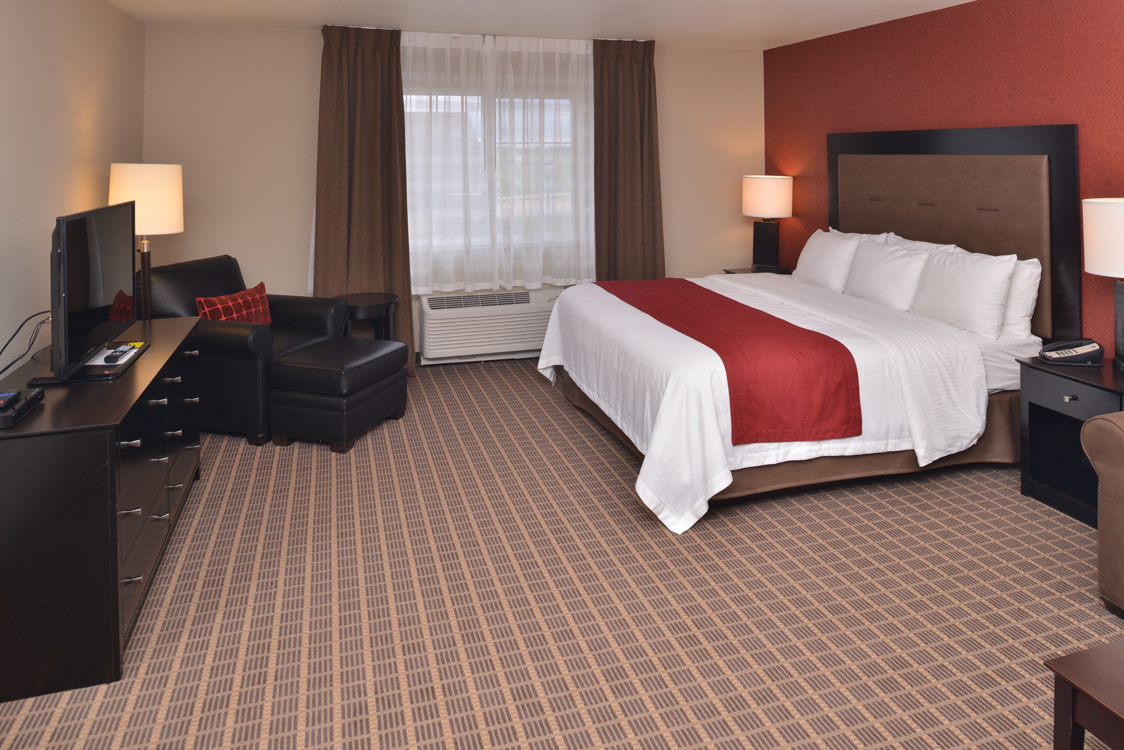 A hotel room with a large bed, a desk with a computer, a chair, and a TV.