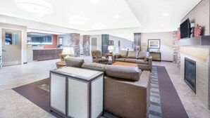 Amplia sala de estar con chimenea, cocina al fondo y zona de estar con mesa de centro y sofás.