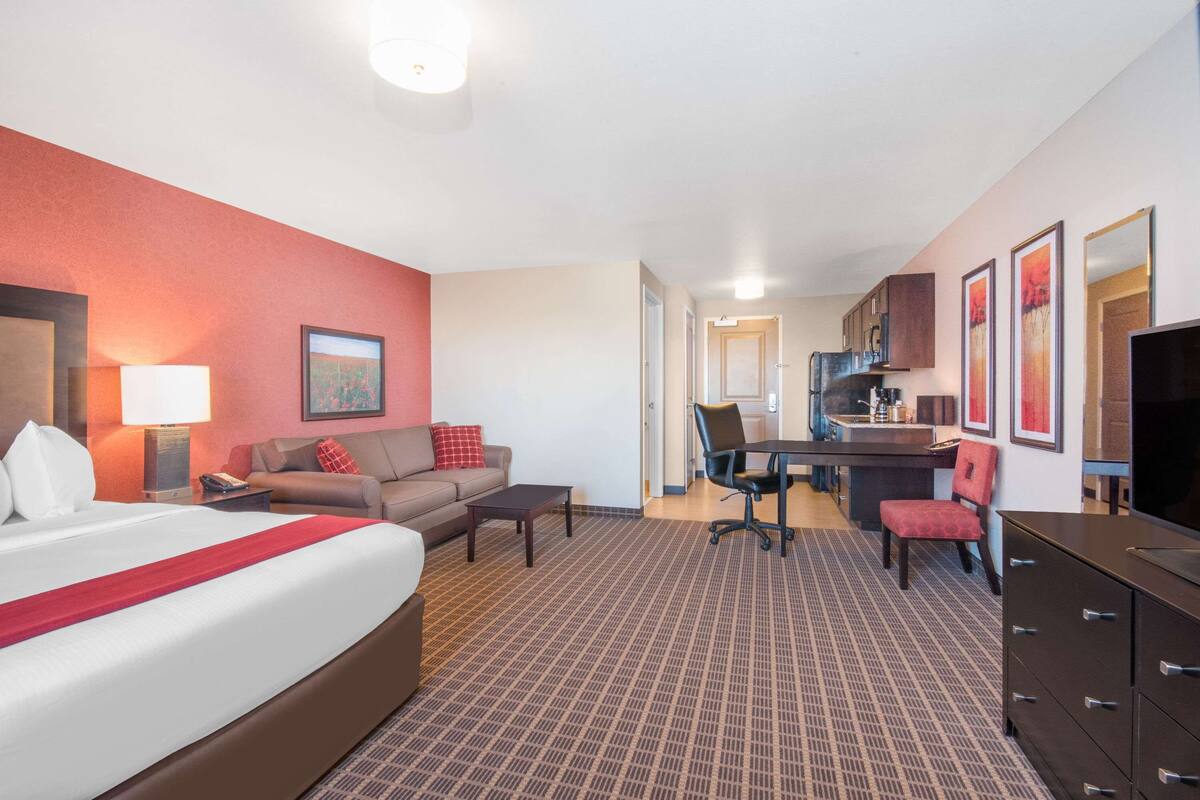 Una habitación de hotel con cama, sofá, escritorio, silla y televisor.