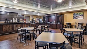 Un restaurante con suelo de madera, mesas y sillas, una barra con productos alimenticios y un cuadro en la pared.