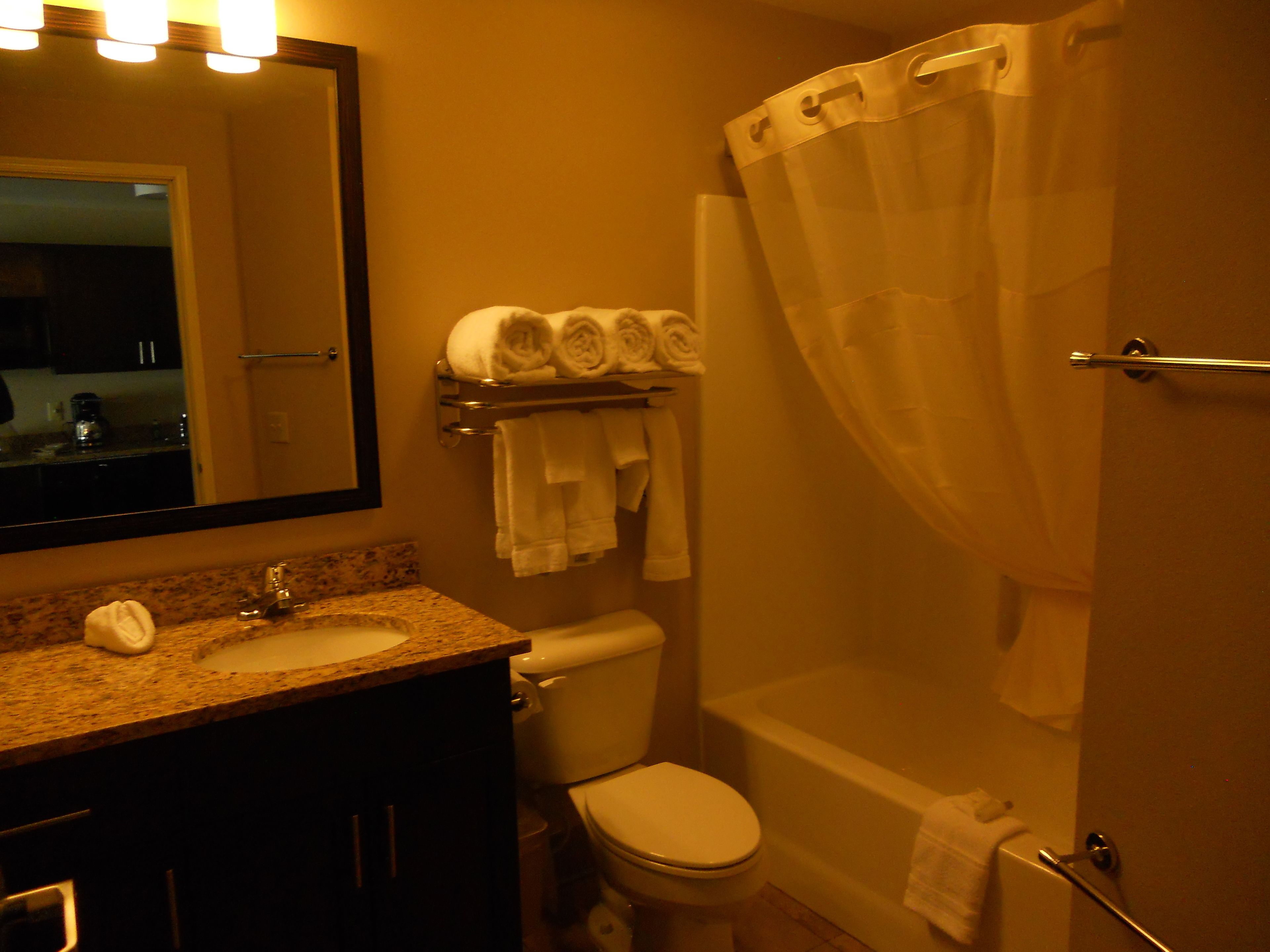 A bathroom with a sink, toilet, and bathtub. There are towels on the wall and a shower curtain.