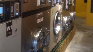 A row of industrial-style washers with control panels and signage, likely in a laundromat or similar facility. - Oriental Hotel (George Town)