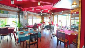 A restaurant with red walls, multiple tables, and chairs. - Oriental Hotel (George Town)