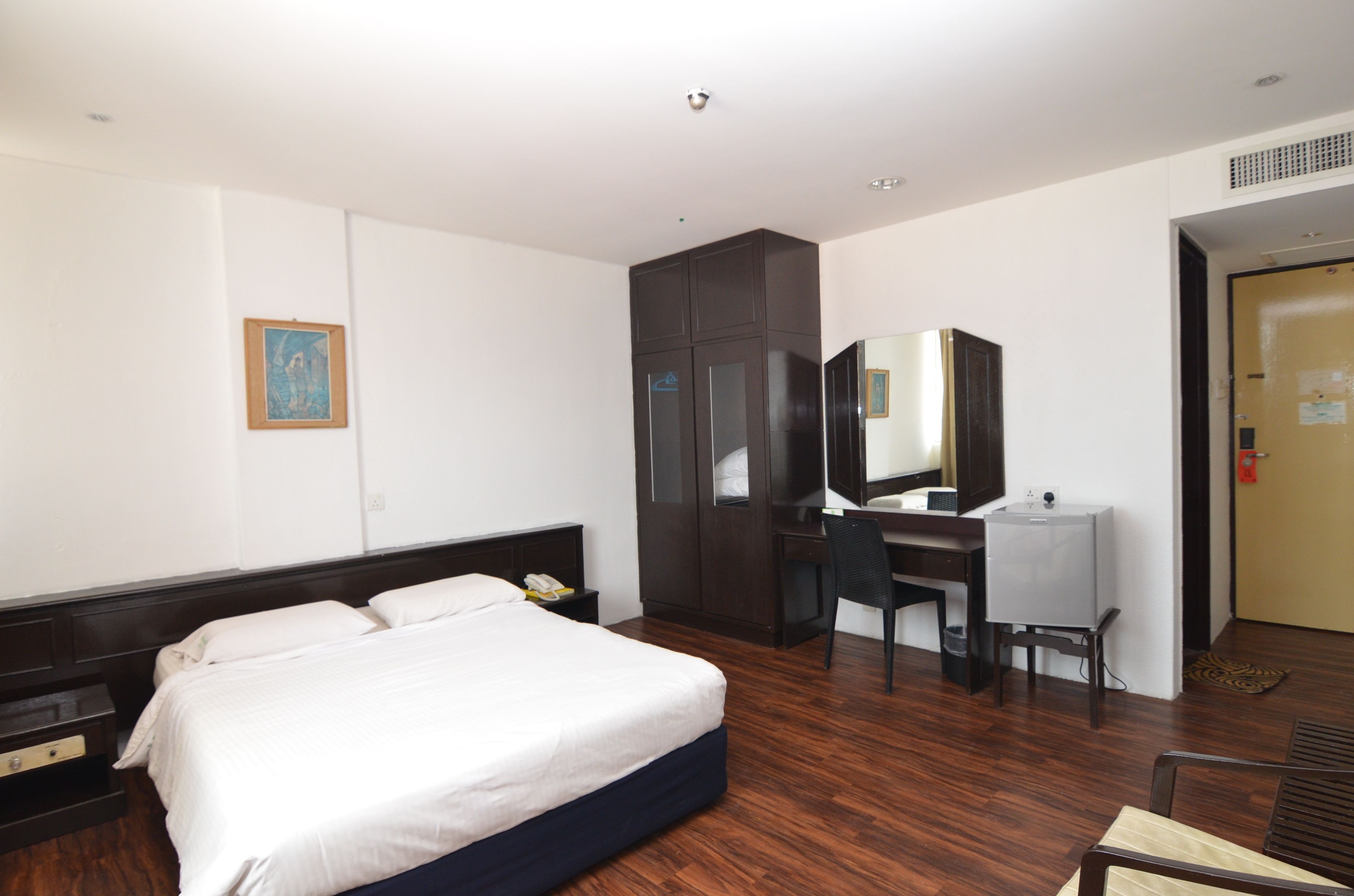 Una habitación de hotel con cama, escritorio, silla y armario.