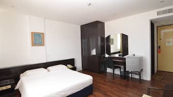 Una habitación de hotel con cama, escritorio, silla y armario.