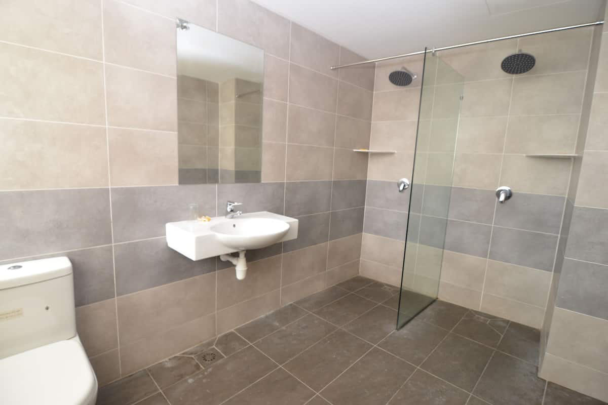 A bathroom with a toilet, sink, and glass shower enclosure.