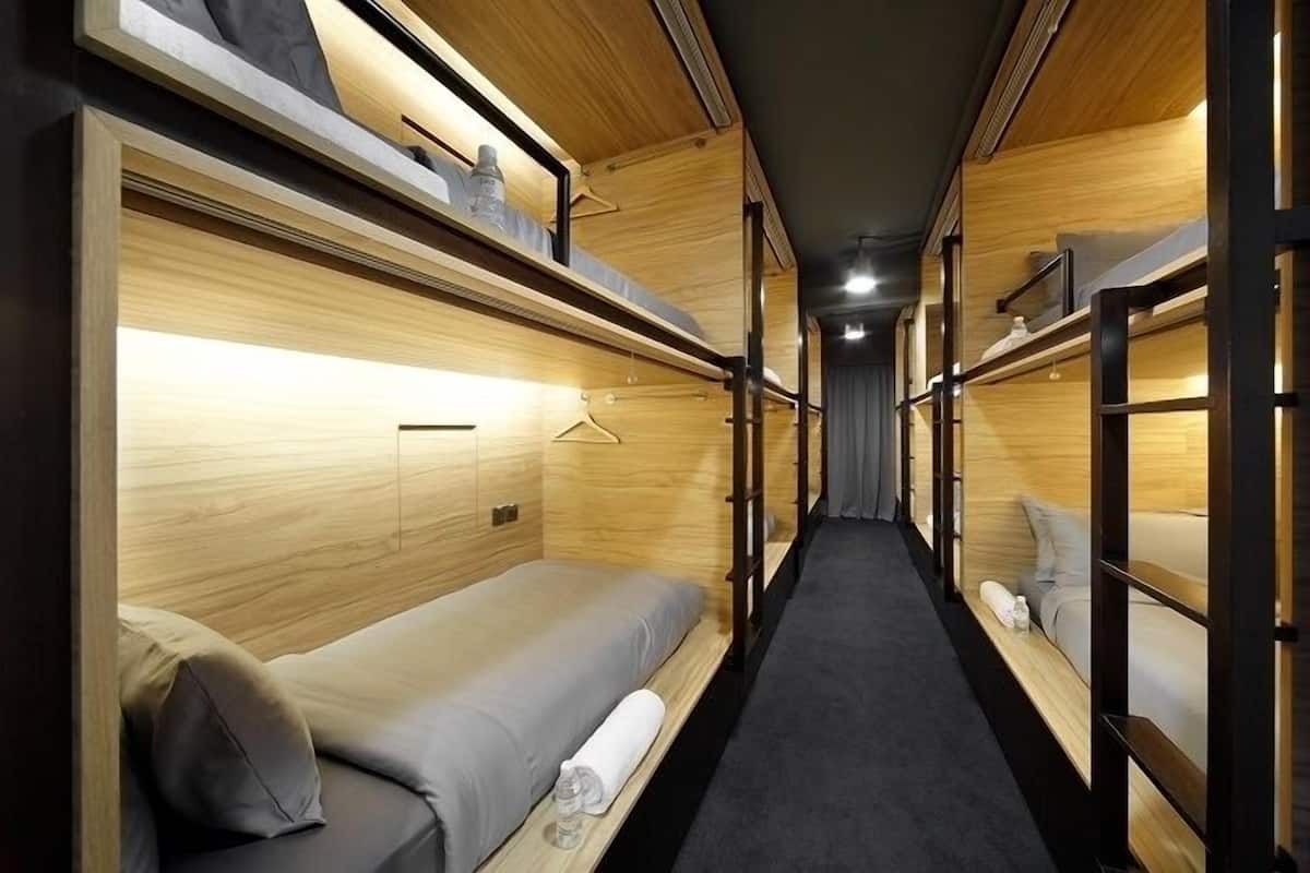A narrow corridor with bunk beds on either side, wooden walls, and a carpeted floor.