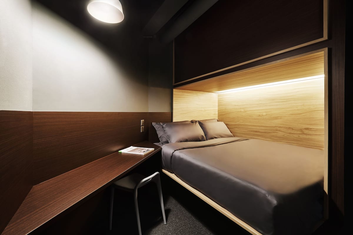A compact room with a bed, a desk, and a chair.