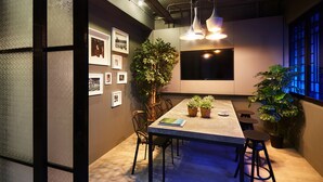 Un salón de conferencias moderno con una mesa larga, sillas, plantas en macetas y obras de arte colgadas en la pared.