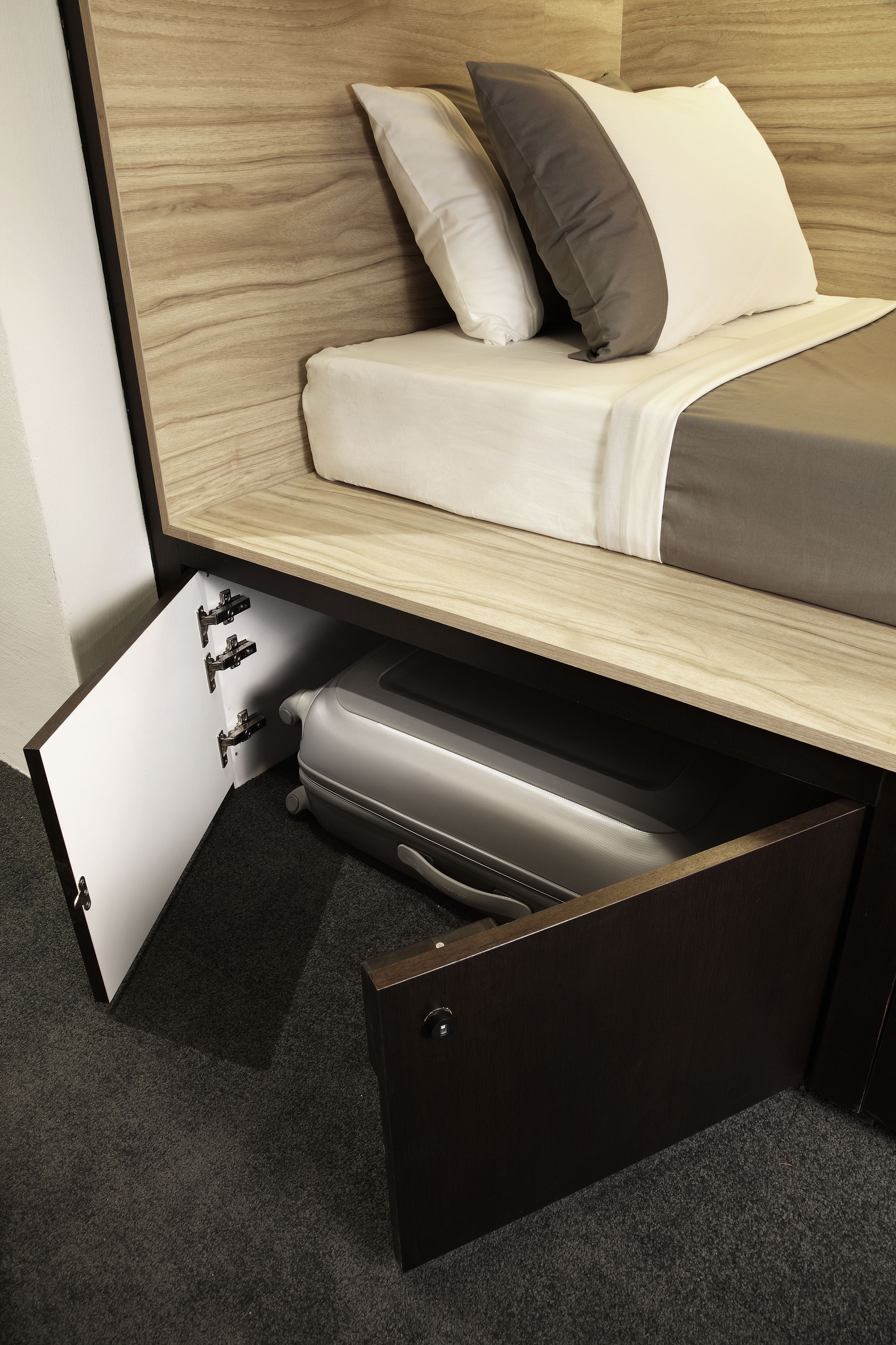 A bed with a wooden headboard, two pillows, and a drawer under the bed.