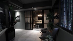 Un interior moderno con zona de comedor, asientos y una cocina visible a través de un panel de vidrio.