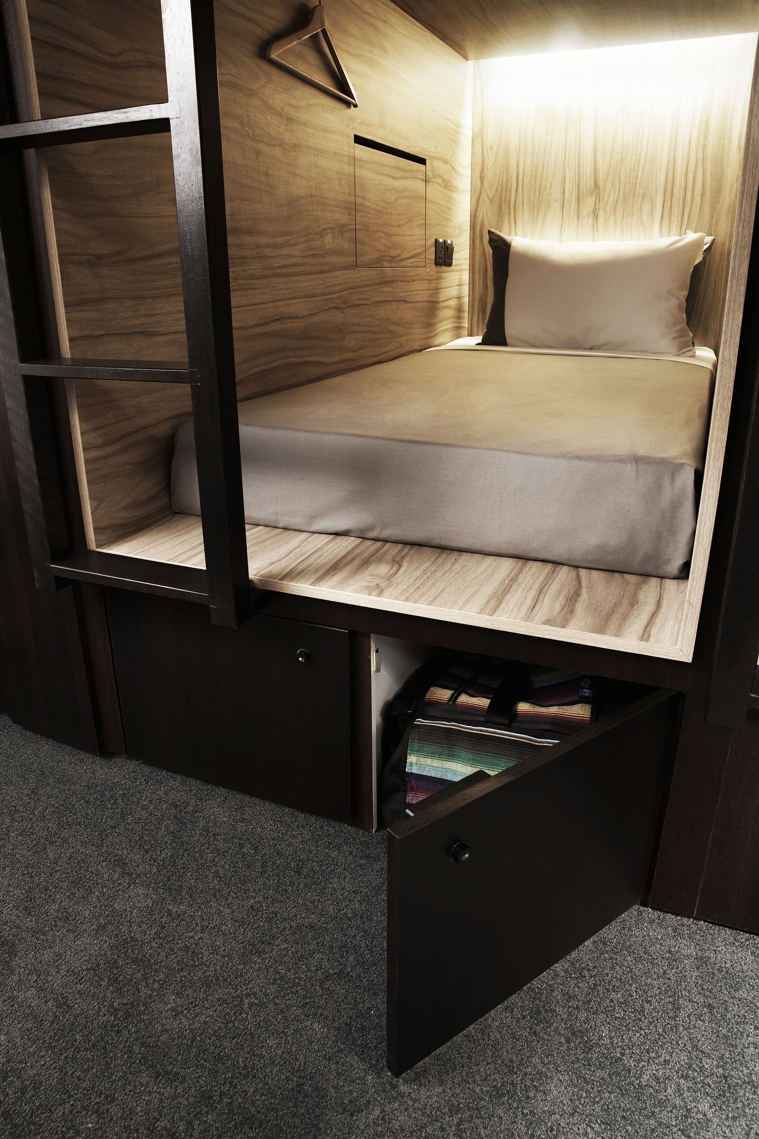Un lit compact avec un cadre en bois et un tiroir coulissant situé en dessous.