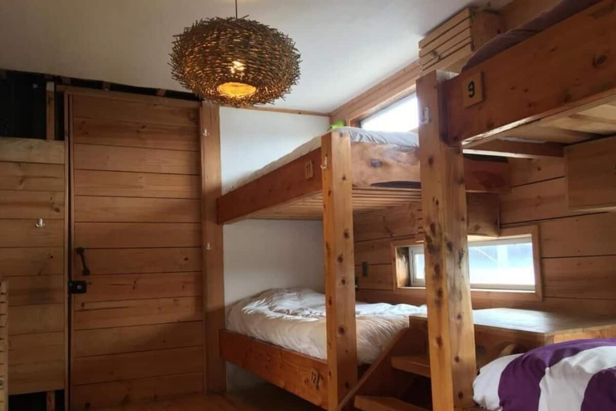 Una cabaña de madera con literas, una lámpara de fibra y una ventana.