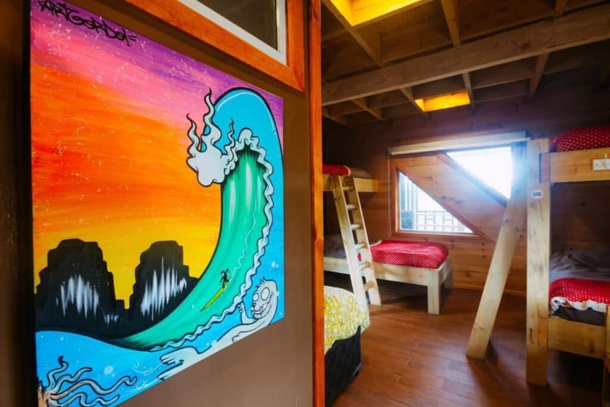Una habitación con literas, una escalera y un mural colorido en la pared.
