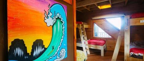 Una habitación con literas, una escalera y un mural colorido en la pared.