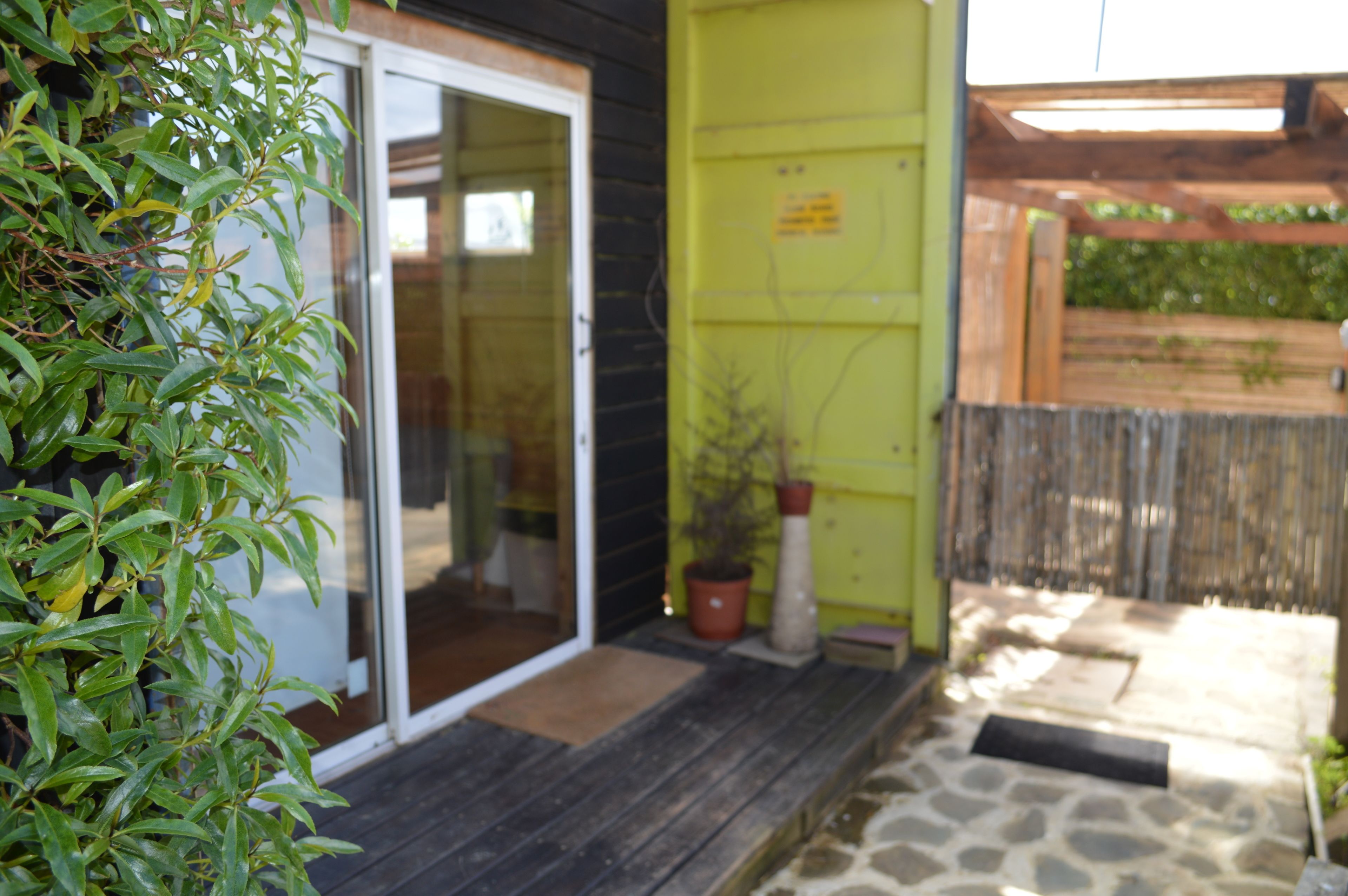 A wooden exterior with a sliding glass door, a small porch area, and a potted plant.