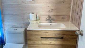 A compact bathroom with a wooden vanity, a toilet, and a sink.