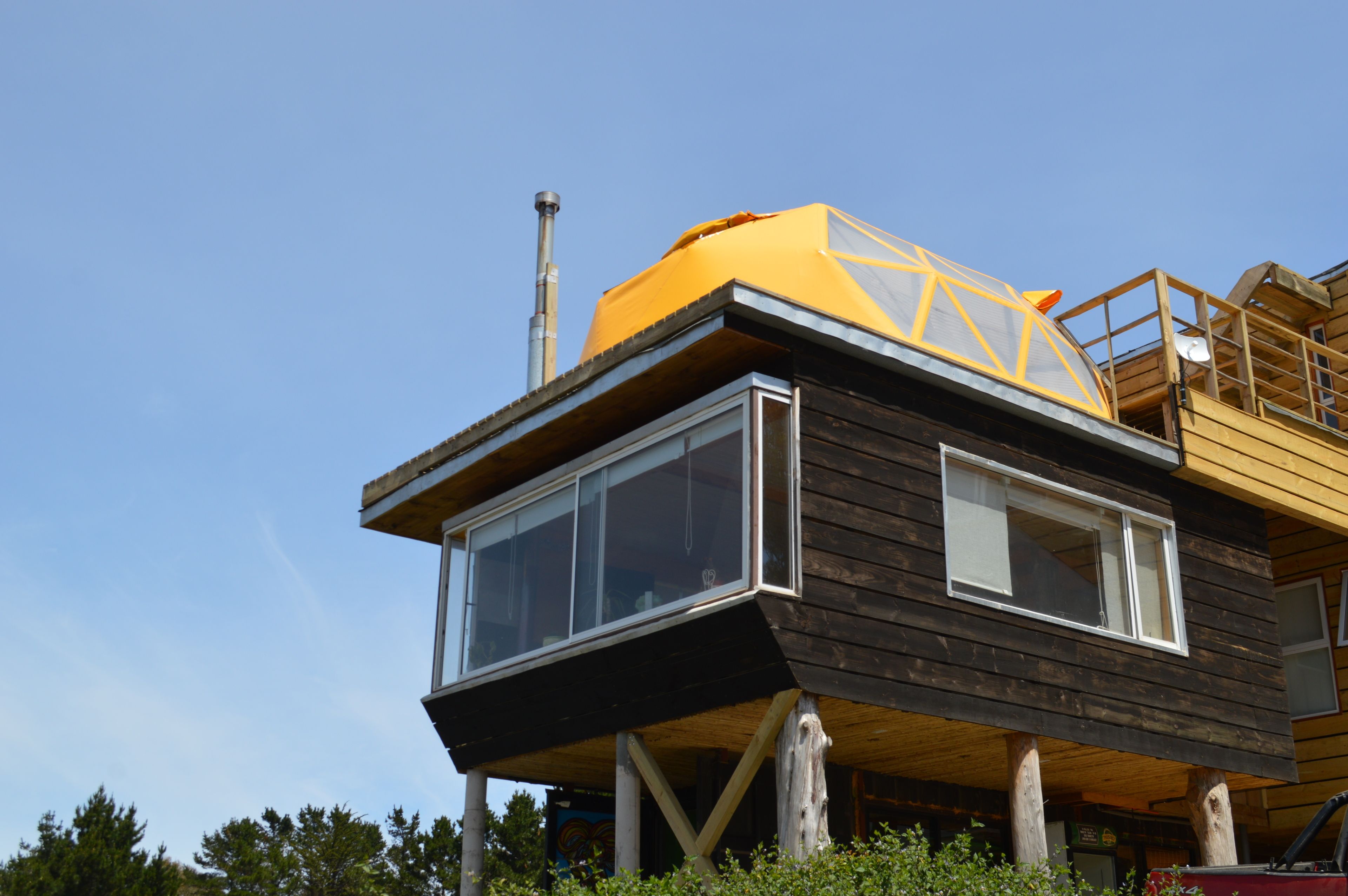 A modern house with a large glass window and a yellow structure on top.