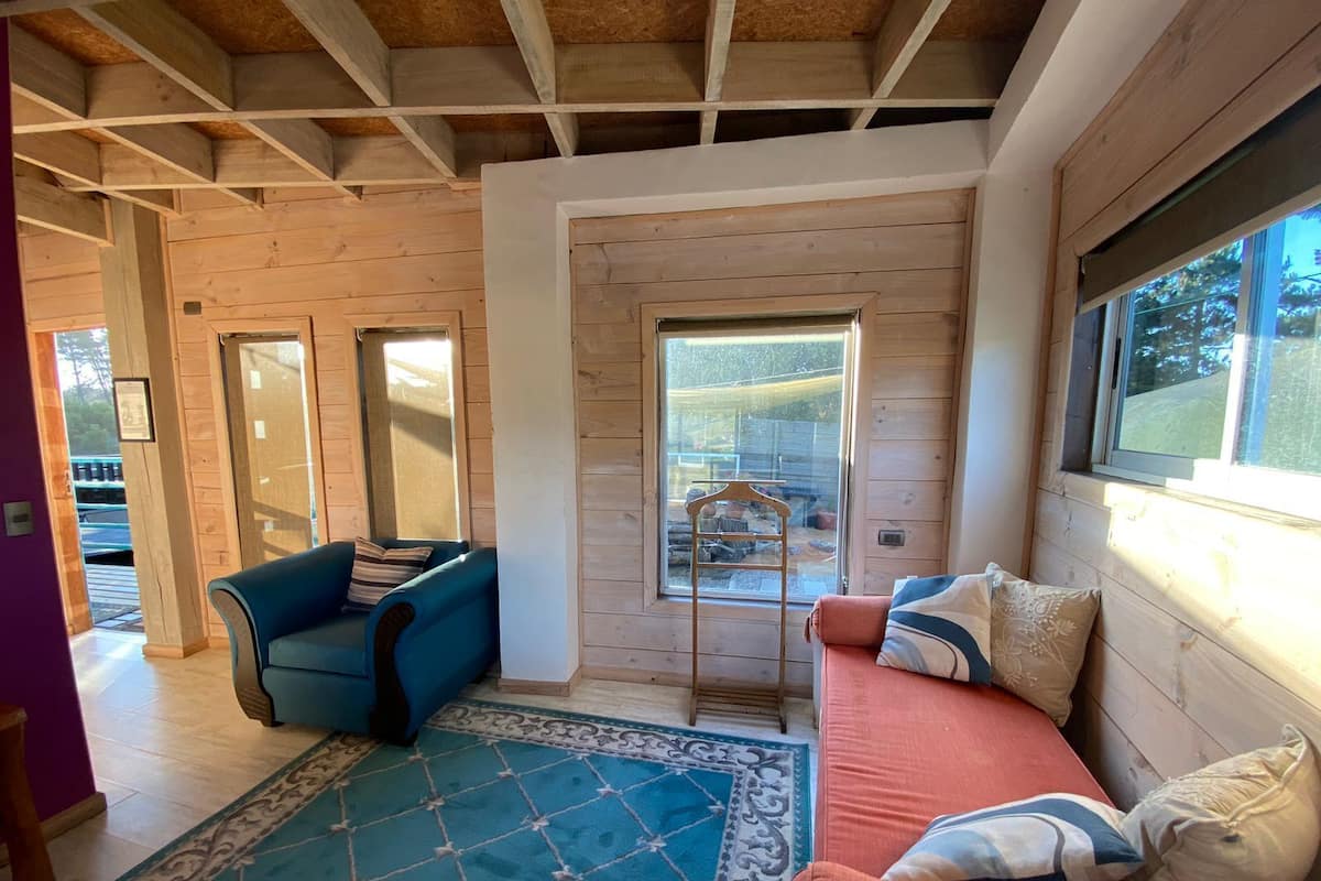 Una sala de estar acogedora con un sofá azul, un sofá rojo y un tapete estampado.