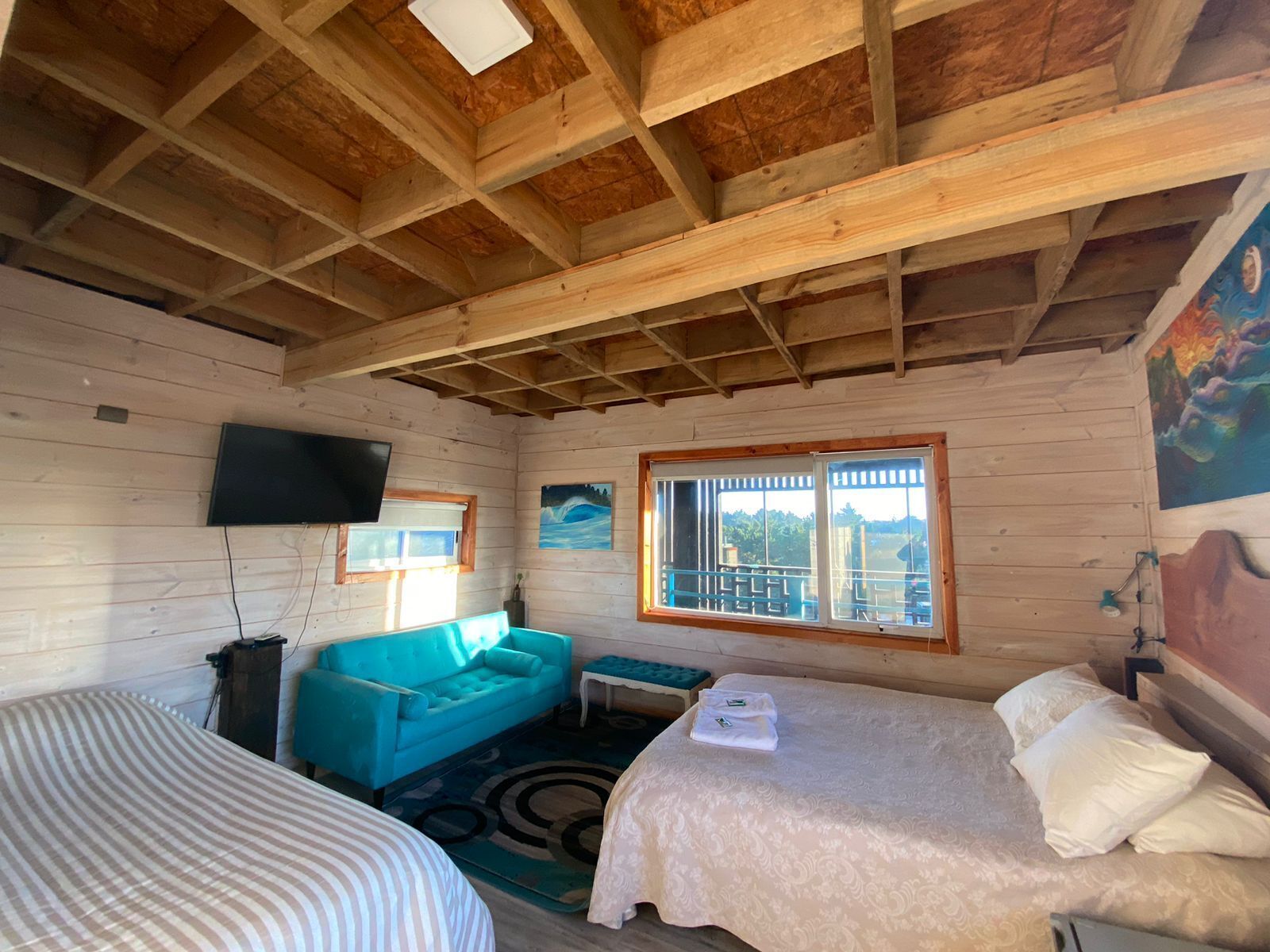 Eine Hütte mit Holzvertäfelung, einem Bett, einer Couch, einem Fernseher und einem Fenster mit Aussicht.