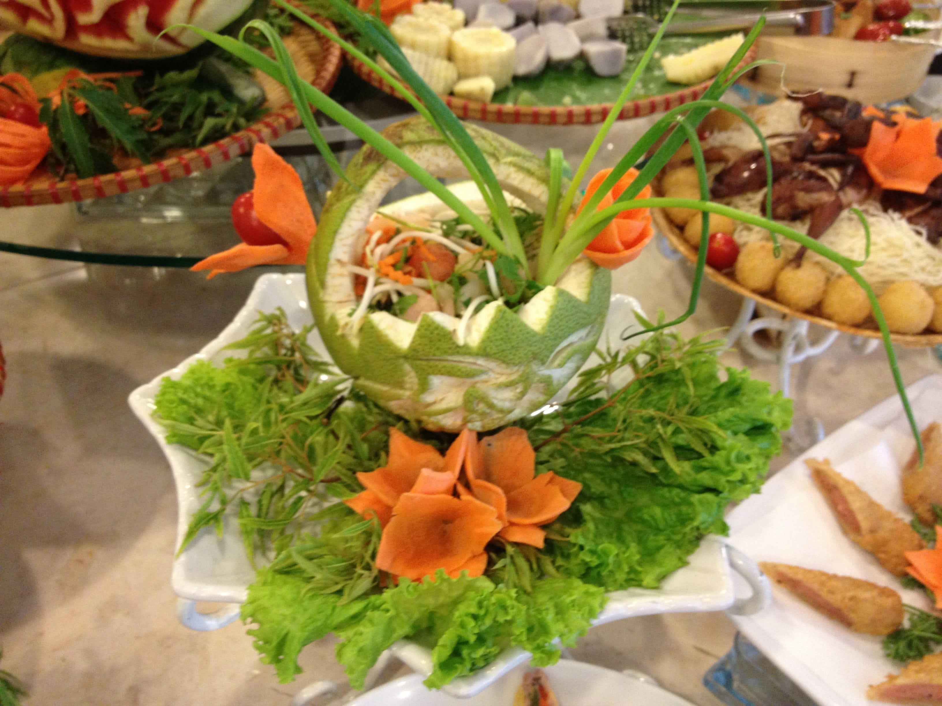 Un bufé con diversos platos, incluyendo un centro de mesa con verduras y carne.
