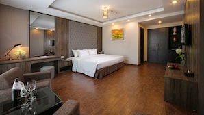 Una habitación de hotel moderna con una cama grande, un escritorio con silla, un televisor y un espejo.