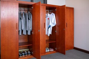 Un armario de madera con múltiples estantes y espacio para colgar, que contiene ropa y zapatos ordenados.
