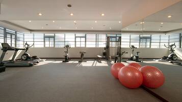 A gym with exercise equipment, large windows, and exercise balls.