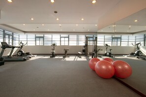 Un gimnasio con equipo de ejercicio, ventanas amplias y pelotas de ejercicio.