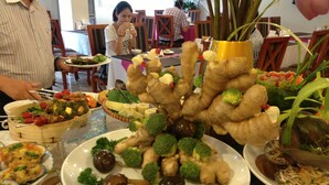 Una mesa de buffet con diversos platos, incluyendo calamares rellenos de carne picada de cerdo, verduras brochetas y otras comidas variadas.
