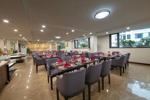 Un comedor amplio con varias mesas y sillas, equipado con iluminación moderna y grandes ventanales que ofrecen vistas al exterior.