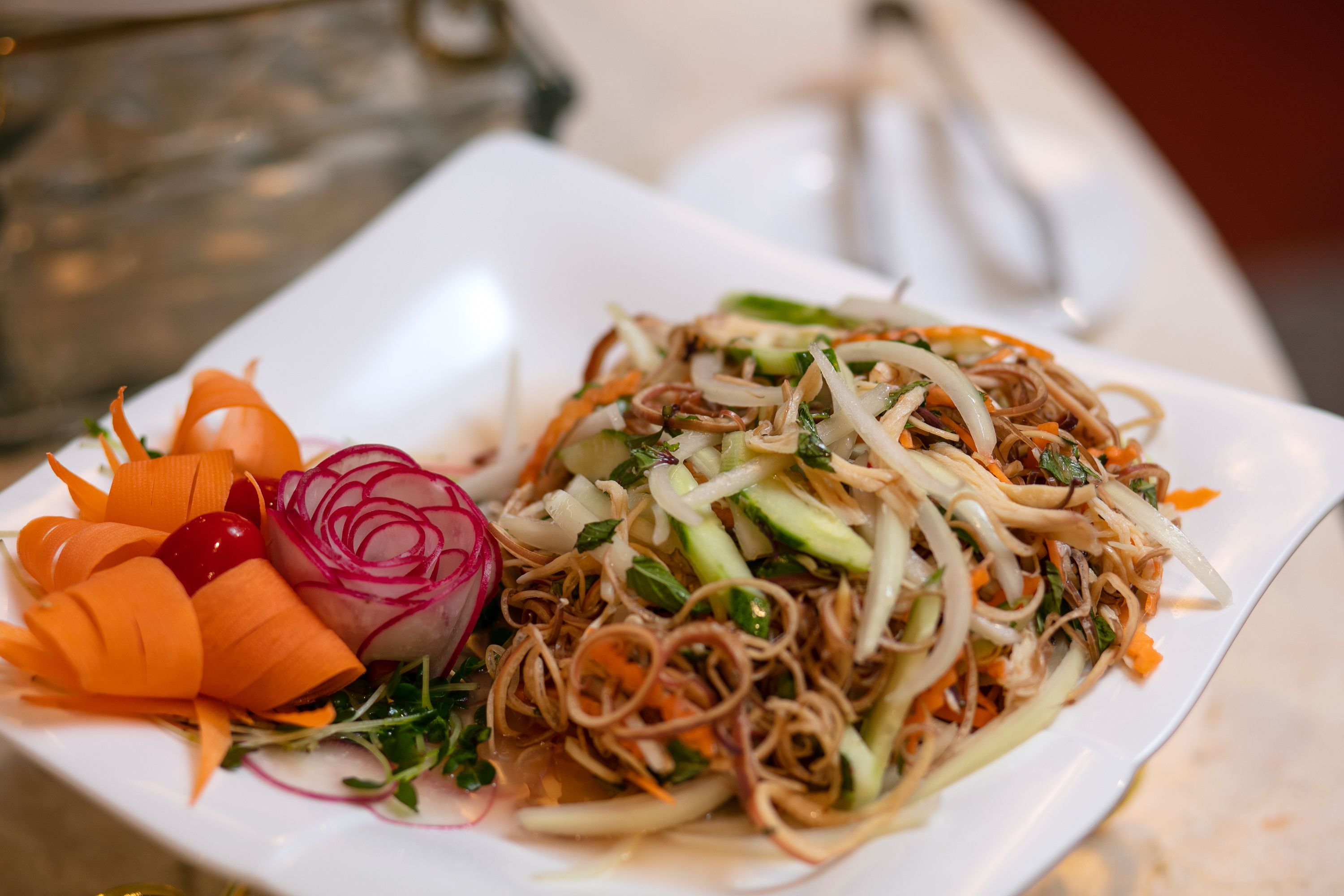 A plate of noodles with vegetables and a side salad.