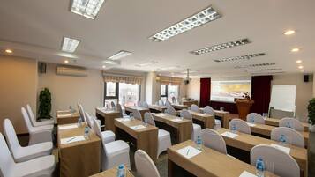 A conference room with tables, chairs, and a presentation screen.