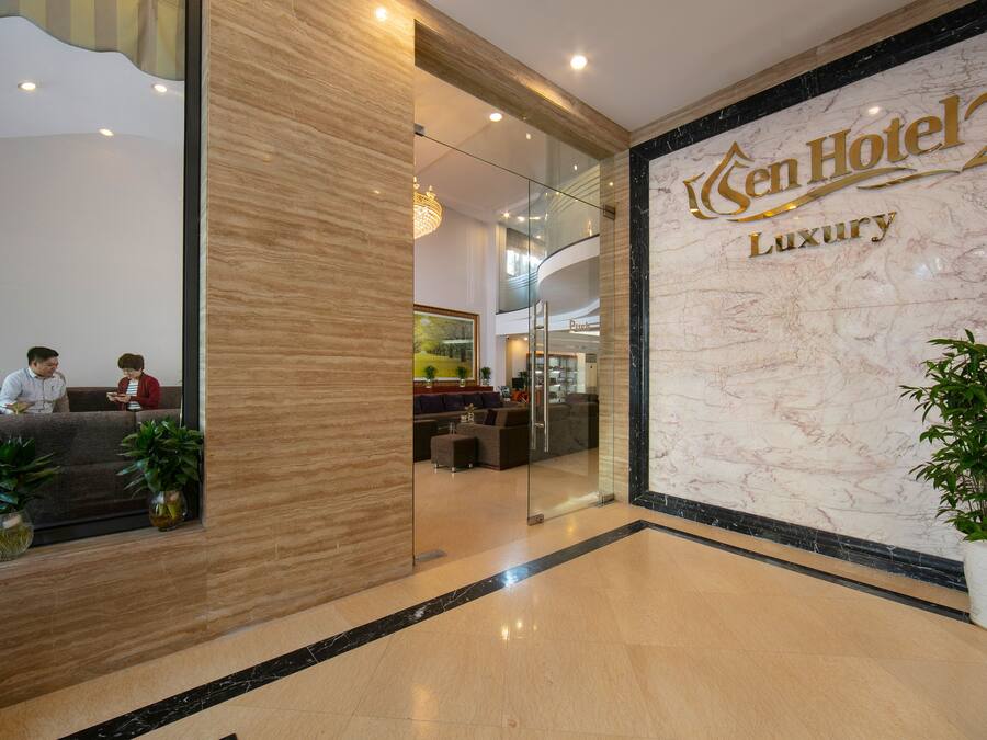 A hotel lobby with a marble reception desk, a glass partition, and a seating area with sofas.