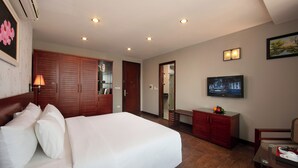 A hotel room with a large bed, a wardrobe, a television, and a desk with a chair. - Sen Hotel (Hanoi)