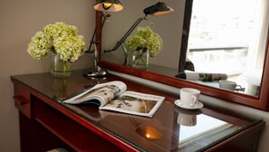 A hotel room with a wooden desk, a magazine, a cup, and two vases of flowers. - Sen Hotel (Hanoi)