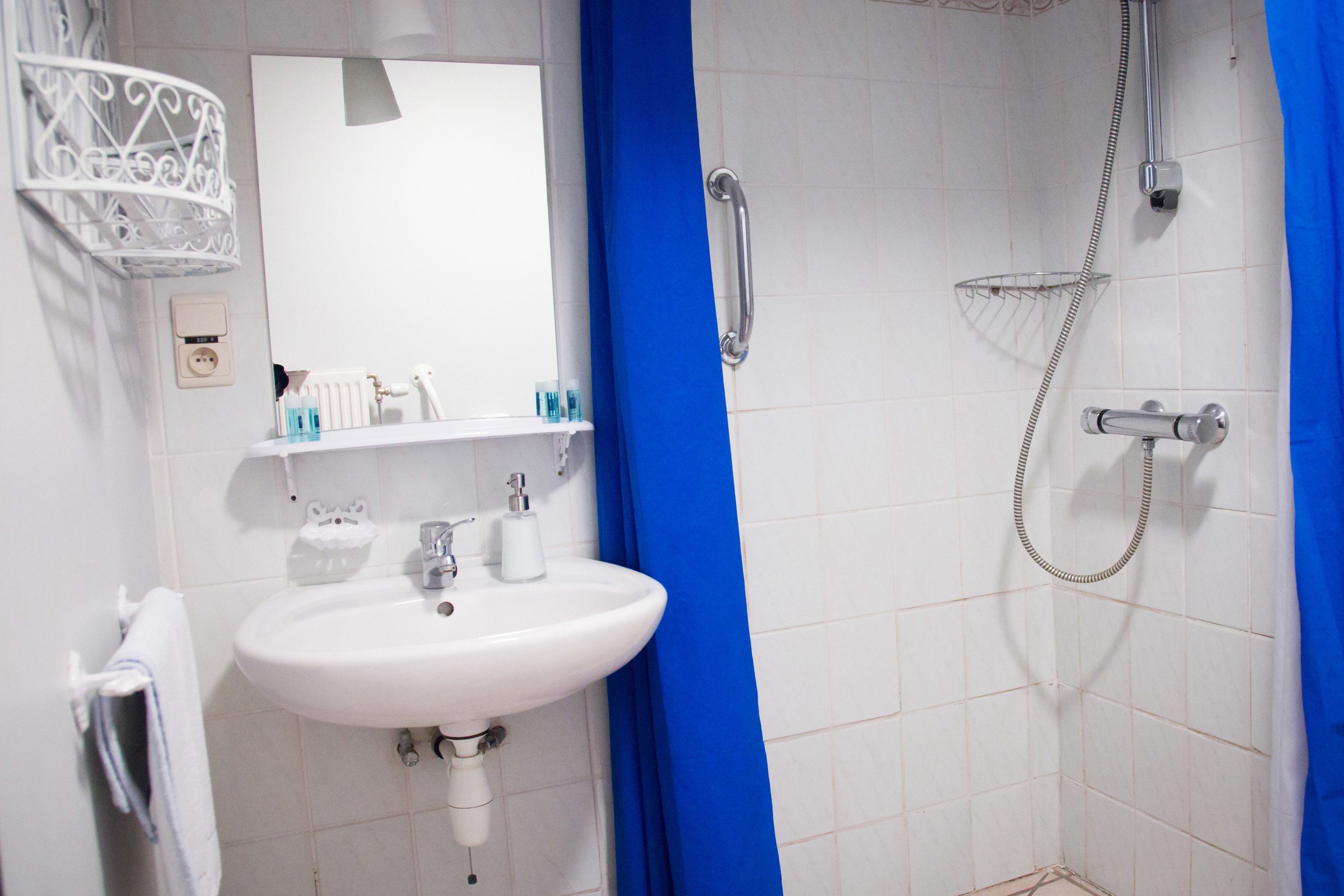 Une salle de bain avec un lavabo blanc, un miroir et une douche.