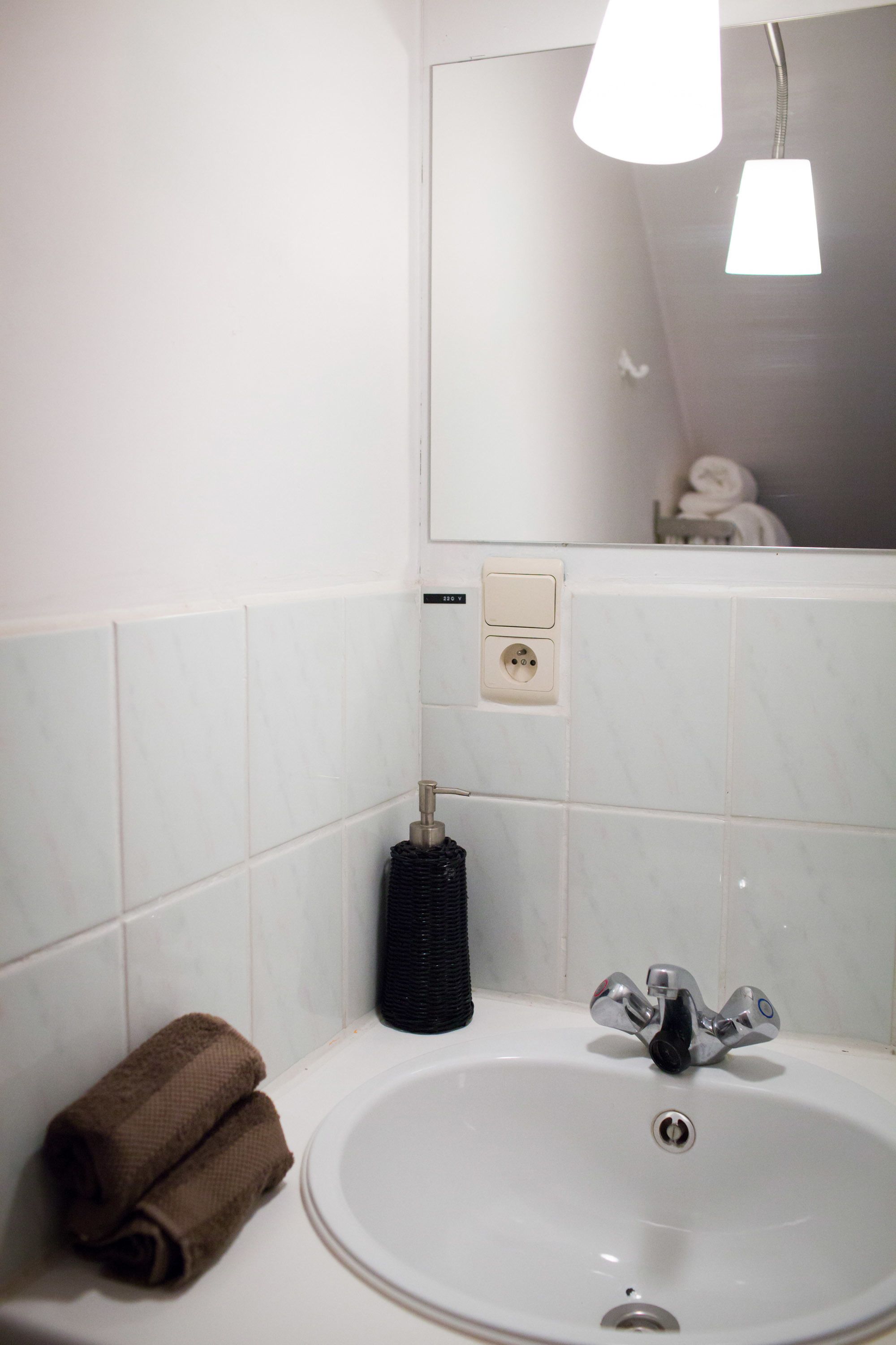 A bathroom with a white sink, a mirror, and a towel rack.