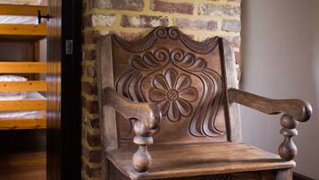 Une chaise en bois ornée de sculptures complexes, placée devant un mur de briques.