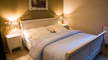 Una cama bien hecha con ropa de cama blanca, un cabecero blanco y dos mesitas de noche con lámparas.